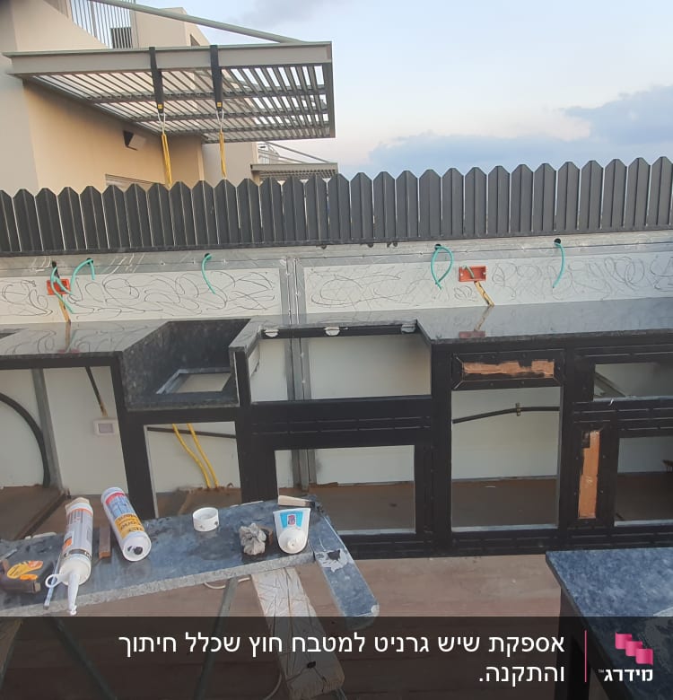 משטחי שיש כהים מותקנים במטבח חיצוני